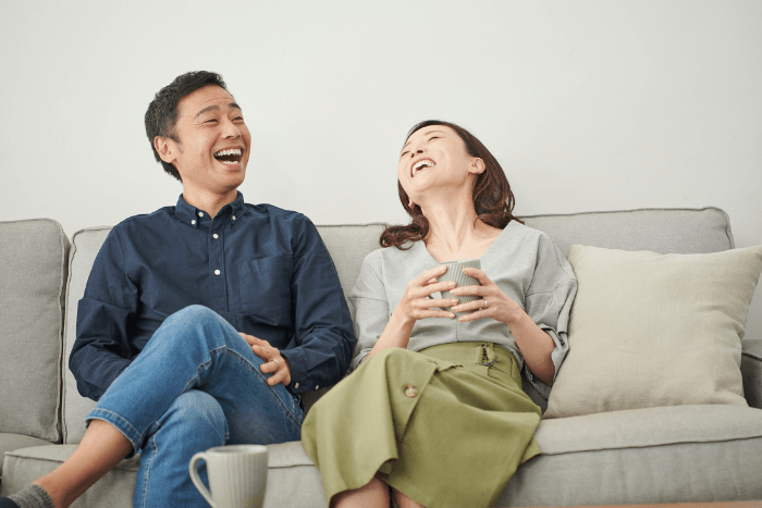 Coppia che ride insieme, simbolo di connessione umana ed empatia: l’importanza del legame autentico nella relazione d’aiuto, oltre l’intelligenza artificiale.